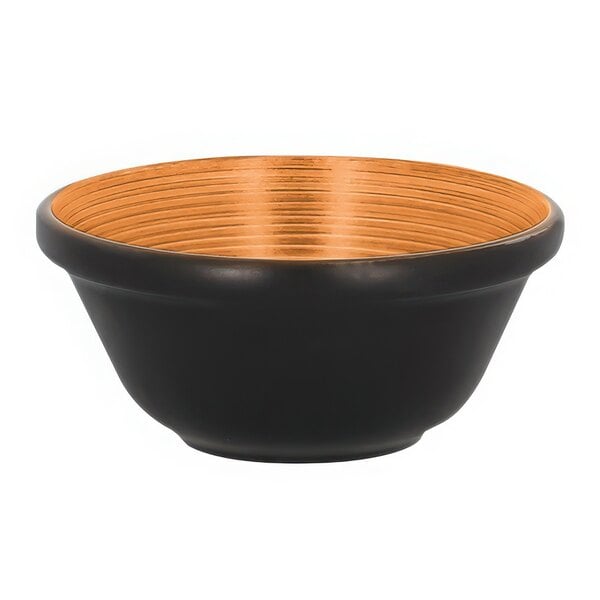 A black bowl with a gold rim and wooden accents.