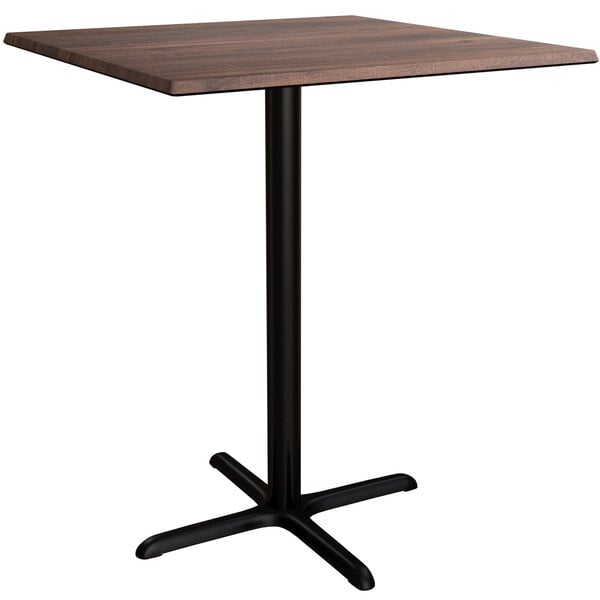 A Lancaster Table & Seating square bar height table with a walnut top and black base plate.