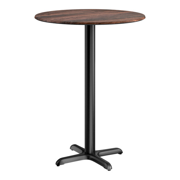 A round bar height table with a textured walnut finish top and a black cross base plate.
