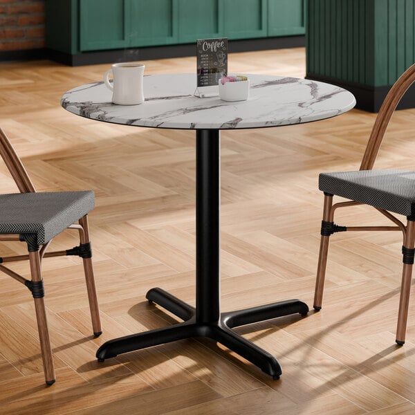 A round standard height table with a smooth Versilla finish and a black cross base plate.