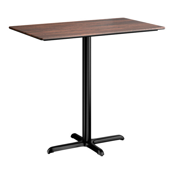 A rectangular bar height table with a textured walnut finish top and a black cross base plate.