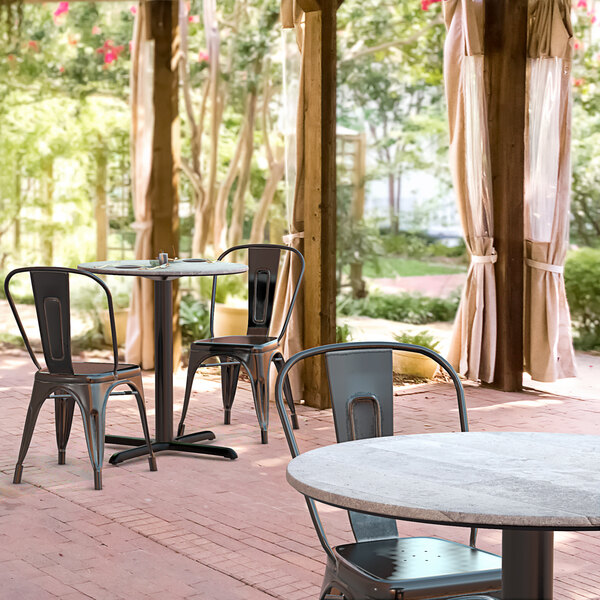 A Lancaster Table & Seating dining table with a cross base plate on an outdoor patio.