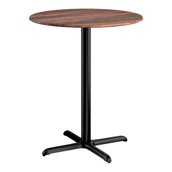 A round bar height table with a textured walnut finish top and a black cross base plate.