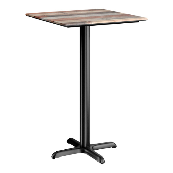 A square bar height table with a textured mixed plank finish top and a black cross base plate.