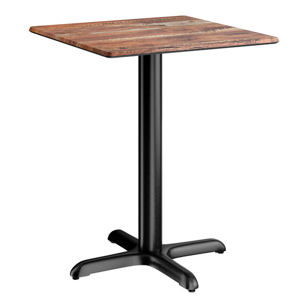 A square standard height table with a textured oak finish top and a black cross base plate.