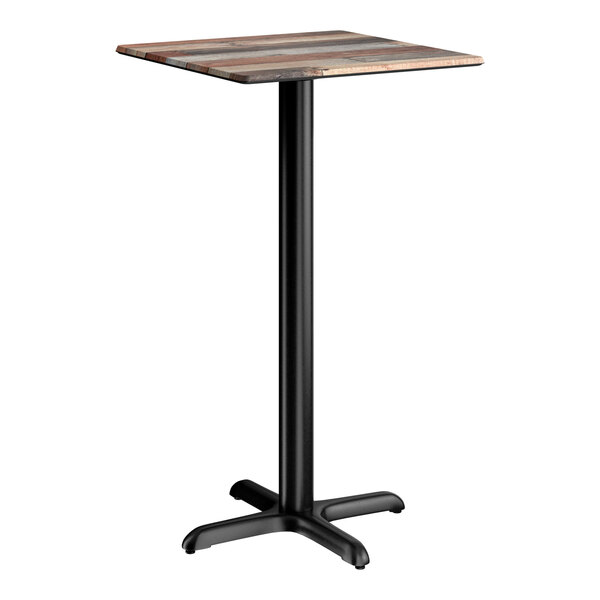 A square bar height table with a textured mixed plank finish top and a black cross base plate.