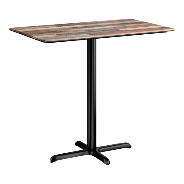 A rectangular bar height table with a textured mixed plank finish top and a black cross base plate.