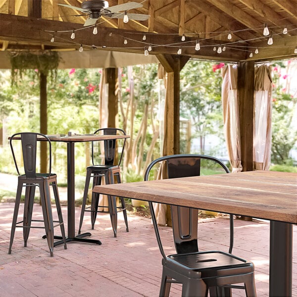 A Lancaster Table & Seating bar height table with textured Yukon Oak finish on a brick patio.