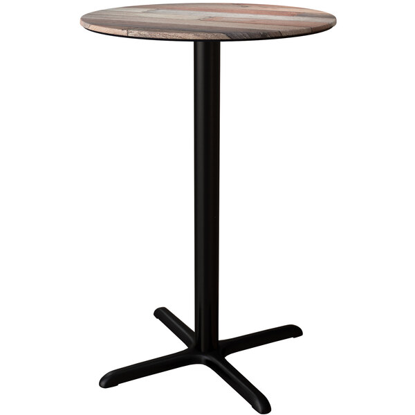 A Lancaster Table & Seating Excalibur round bar height table with a textured mixed plank finish and a black cross base.