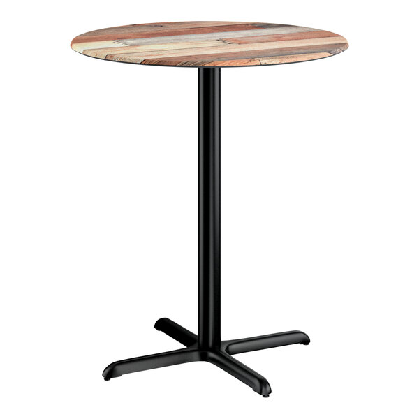 A round bar height table with a textured mixed plank finish top and a black cross base plate.