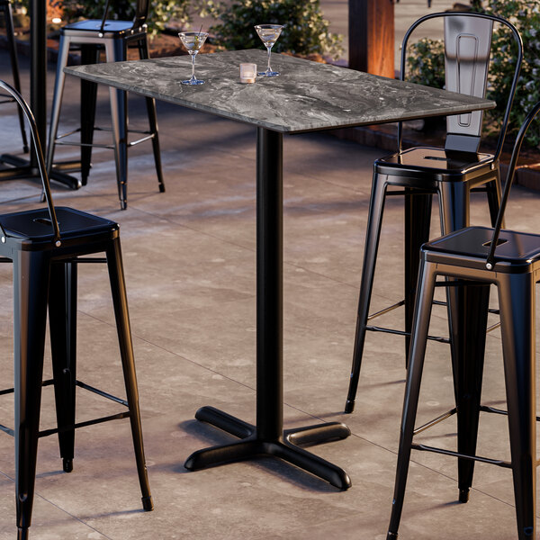 A rectangular bar height table with a smooth dark finish and a cross base plate.