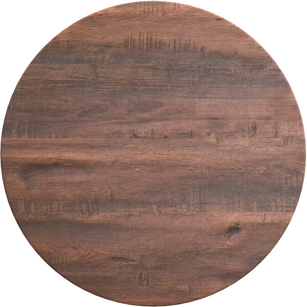 A Lancaster Table & Seating round wooden table top with a dark wood finish on a cross base plate.