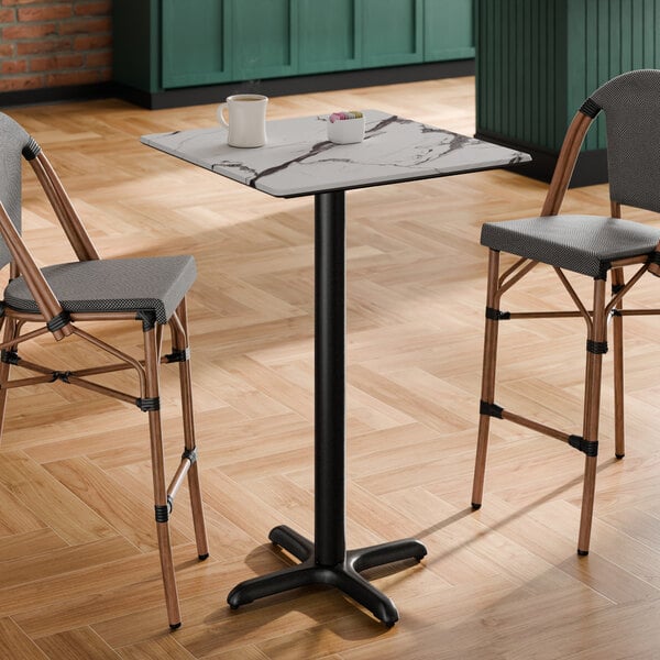 A square bar height table with a smooth Versilla finish top and a black cross base plate.