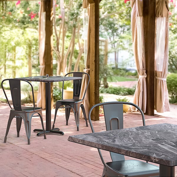 A Lancaster Table and Seating square dining table with chairs on a brick patio.