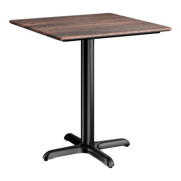 A square standard height table with a textured walnut finish top and a black cross base plate.