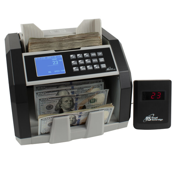 A black Royal Sovereign bill counter with cash on the counter and a digital display.