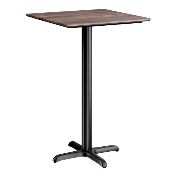 A square bar height table with a textured walnut finish top and a black cross base plate.