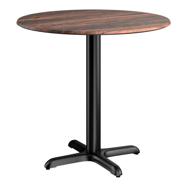 A round standard height table with a textured walnut finish top and a black cross base plate.