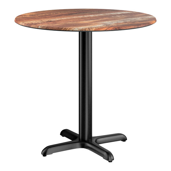 A round standard height table with a textured Yukon oak finish top and a black cross base plate.