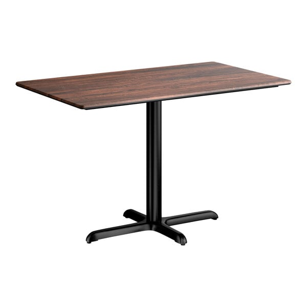 A rectangular standard height table with a textured walnut finish top and a black cross base plate.