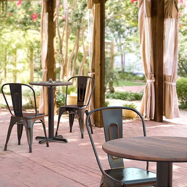 A Lancaster Table & Seating round table with a cross base plate and chairs on a brick patio.