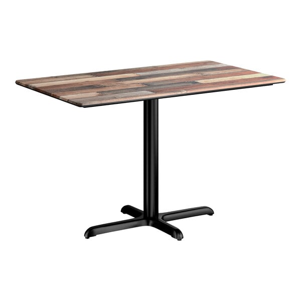 A rectangular standard height table with a textured mixed plank finish top and a black cross base plate.