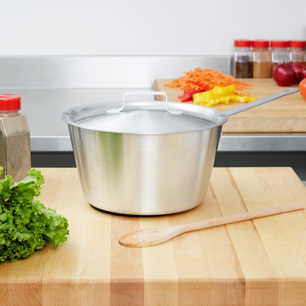A Vollrath stainless steel pot cover on a wooden table.