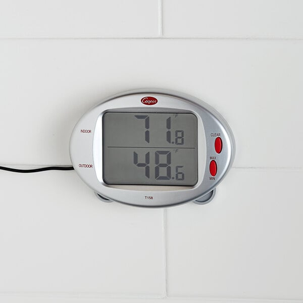 A Cooper-Atkins digital thermometer with remote on a white wall.