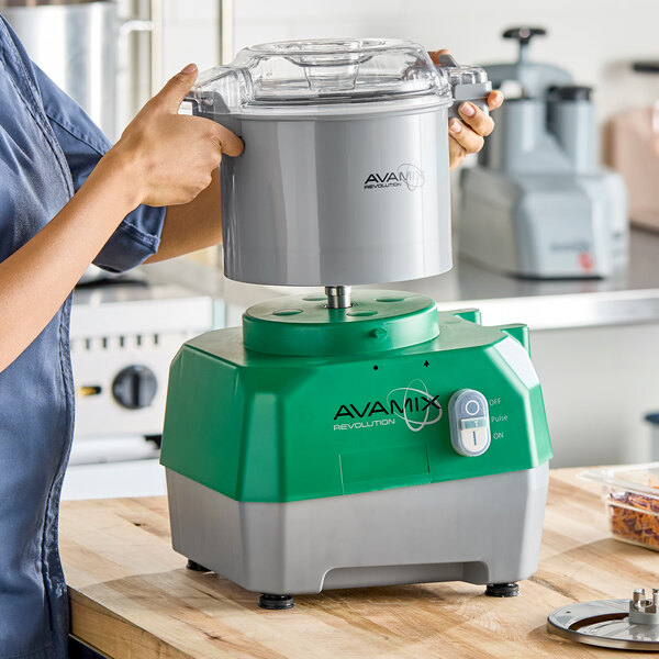 A green and gray AvaMix Revolution combination food processor with a 3-quart plastic bowl being assembled on a kitchen counter.