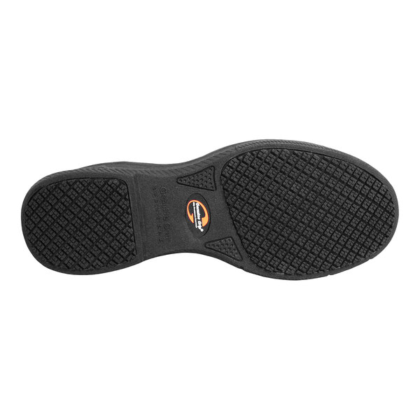 The image shows the black textured sole of a shoe with a small circular logo near the arch area.