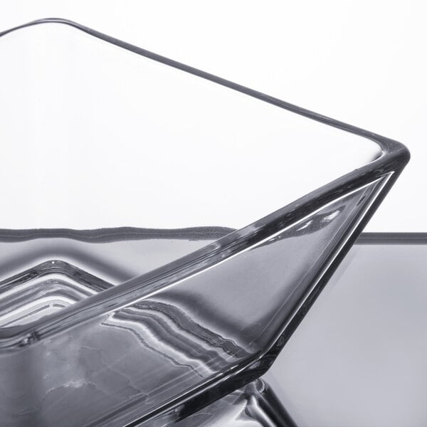 A Libbey square glass bowl with a silver rim on a reflective surface.