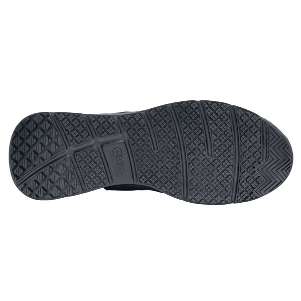A close-up of the black rubber sole of a black Shoes For Crews athletic shoe.