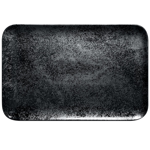 A black rectangular RAK Porcelain plate on a speckled counter.