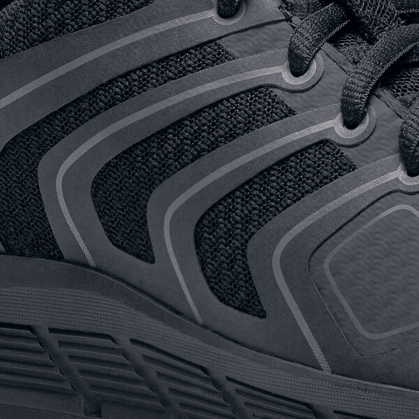 A black Shoes For Crews women's athletic shoe on a table.