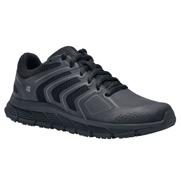 A black Shoes For Crews women's athletic shoe with laces.