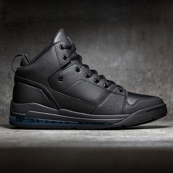 A black Shoes For Crews Tigon men's athletic shoe with blue soles sitting on a grey surface.