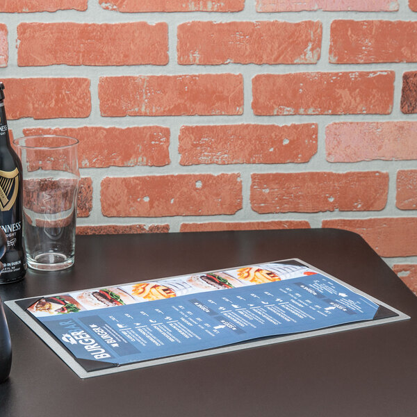 A Menu Solutions Alumitique menu board on a table with a glass of beer.