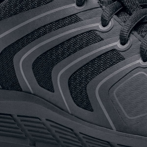 A black Shoes For Crews women's athletic shoe on a table.