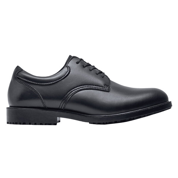 A black Shoes For Crews men's dress shoe with a rubber sole.