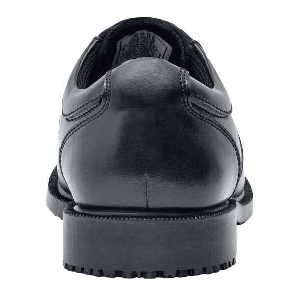 A close up of a black leather Shoes For Crews Cambridge men's dress shoe with a rubber sole.