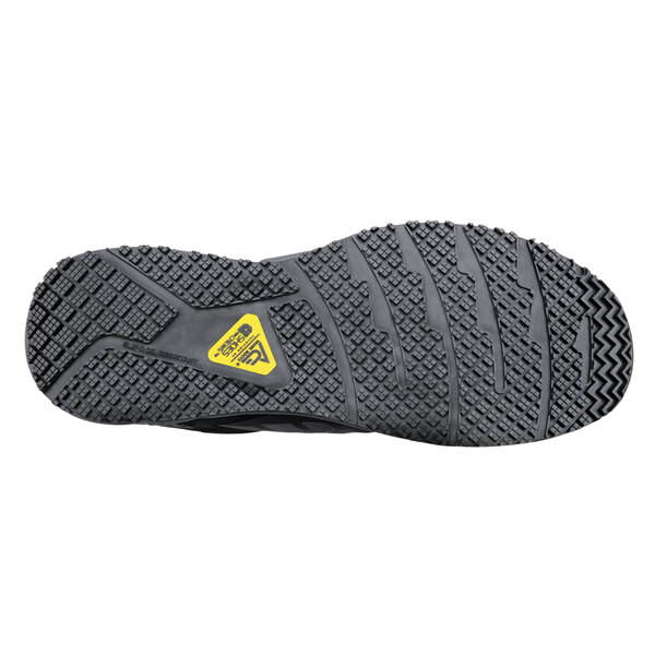 The sole of a black ACE Aster athletic shoe with yellow accents.