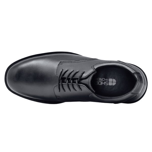 A black Shoes For Crews men's dress shoe with laces.