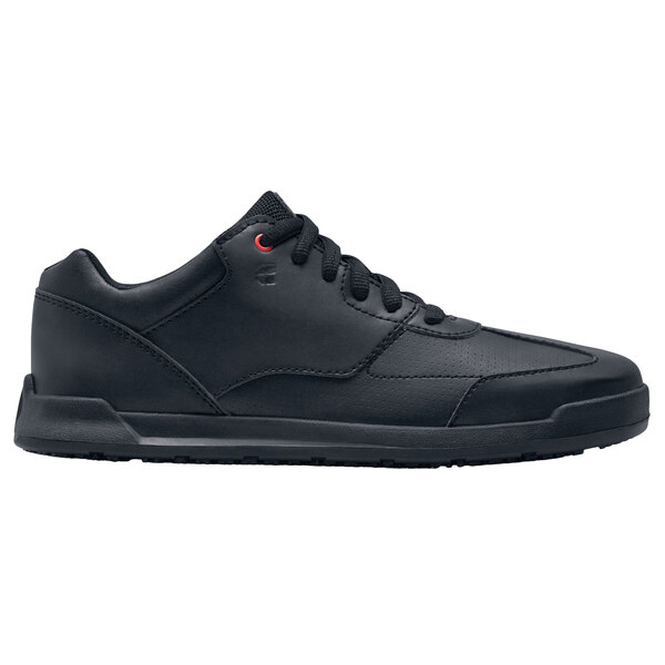 A black Shoes For Crews athletic shoe with red laces.