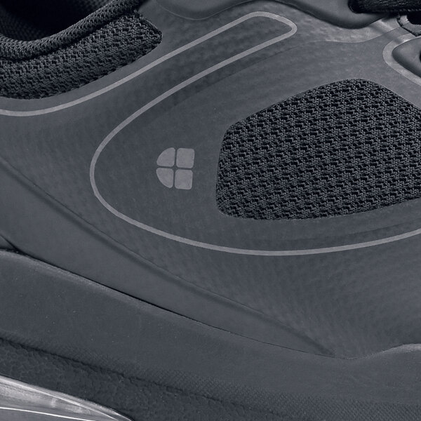 A close up of a black Shoes For Crews Revolution II women's athletic shoe on a table.