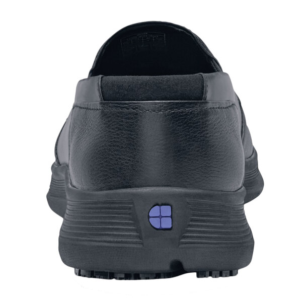 A close-up of a black Shoes For Crews Arden men's casual shoe with a blue square logo on the side.