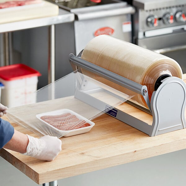 A person wrapping sausages in Western Plastics meat wrapping film on a counter.