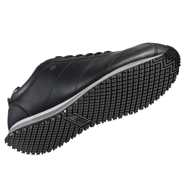 A black Shoes For Crews women's athletic shoe with a white sole.