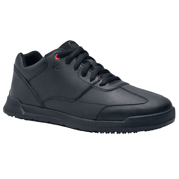 A black Shoes For Crews women's athletic shoe with black and red laces.