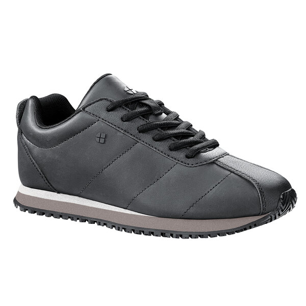 A black Shoes For Crews women's athletic shoe with a white sole.
