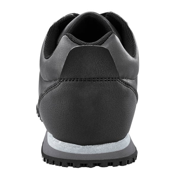 The bottom of a black Shoes For Crews Avery athletic shoe with a white sole.